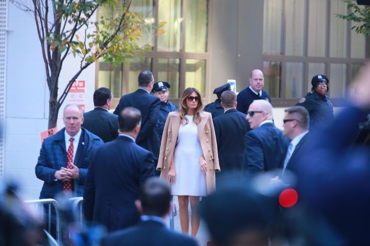 Melania Trump in a white dress with a camel coat