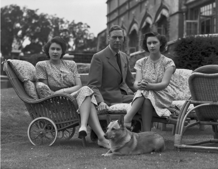 Елизавета и Маргарет с отцом Георгом VI. В ногах у Лилибет — ее корги Сьюзен, 1946 год